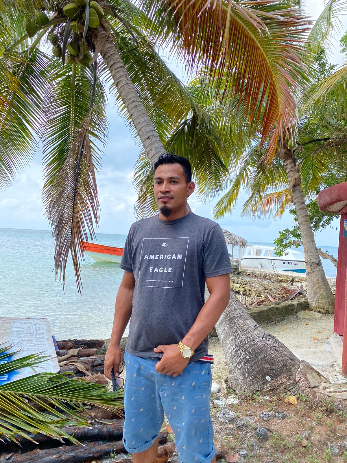 a man standing next to a palm tree next to a body of water